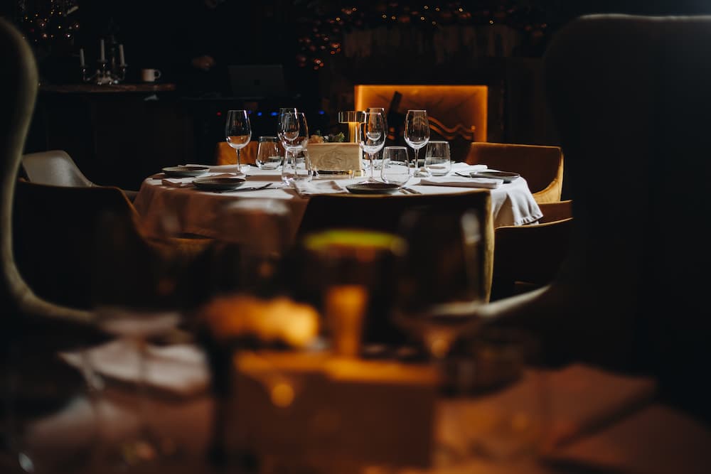 An elegantly set round table in a dim, upscale restaurant, illustrating the perfect fine dining experience for golfers after a round at the 19th hole.